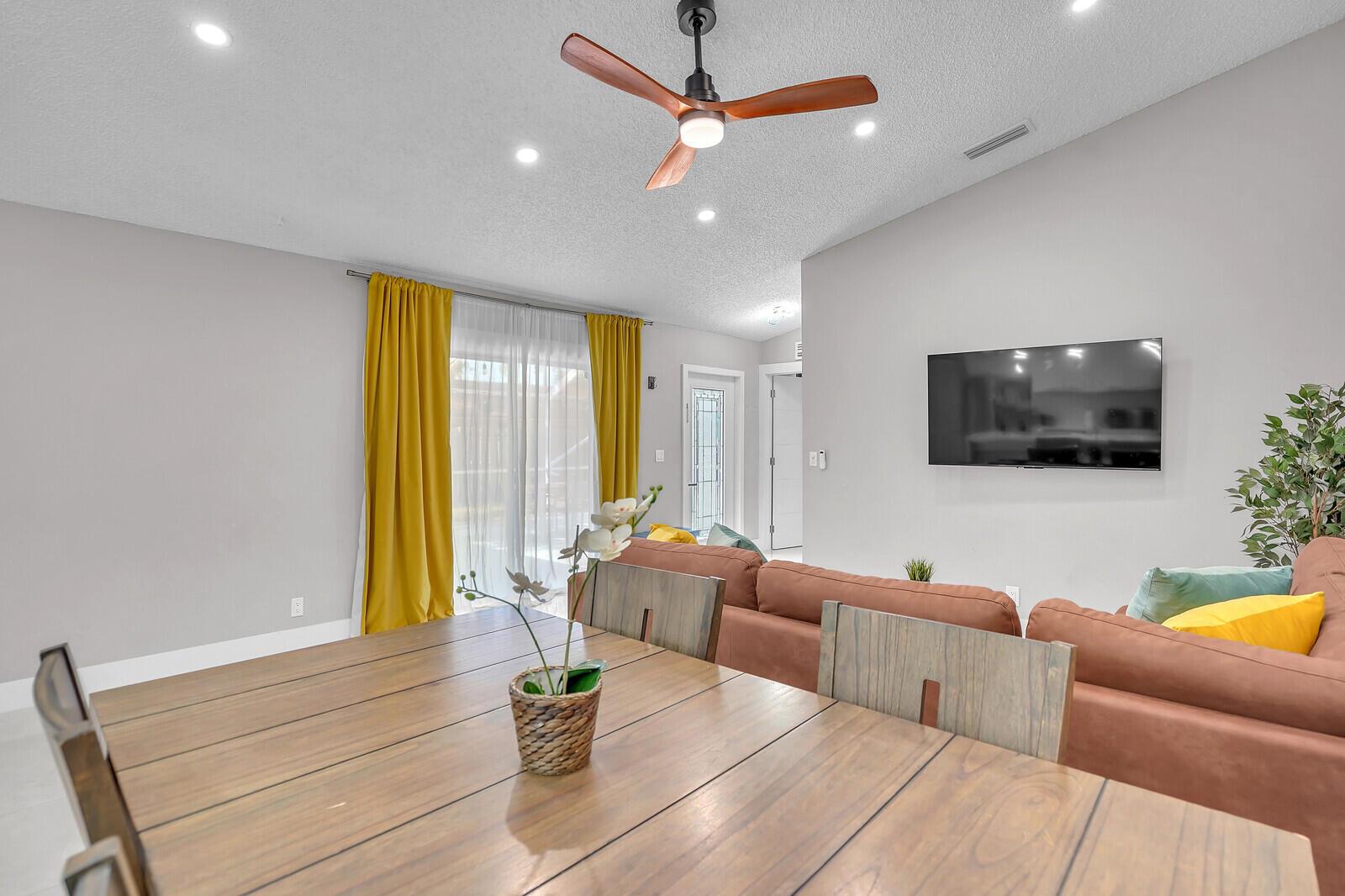A dining area with a wooden table overlooks a living room featuring a brown sofa — 1329 Periwinkle Place, Wellington FL 33414, WELLINGTON, FL