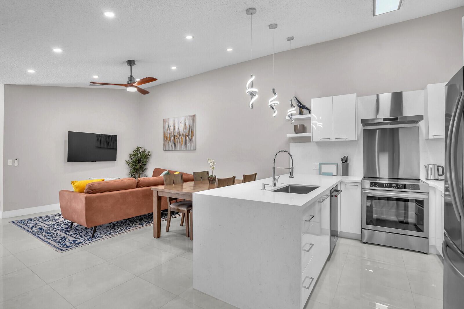 A modern open-concept kitchen and living area with white cabinetry, a central island, and sofa — 1329 Periwinkle Place, Wellington FL 33414, WELLINGTON, FL