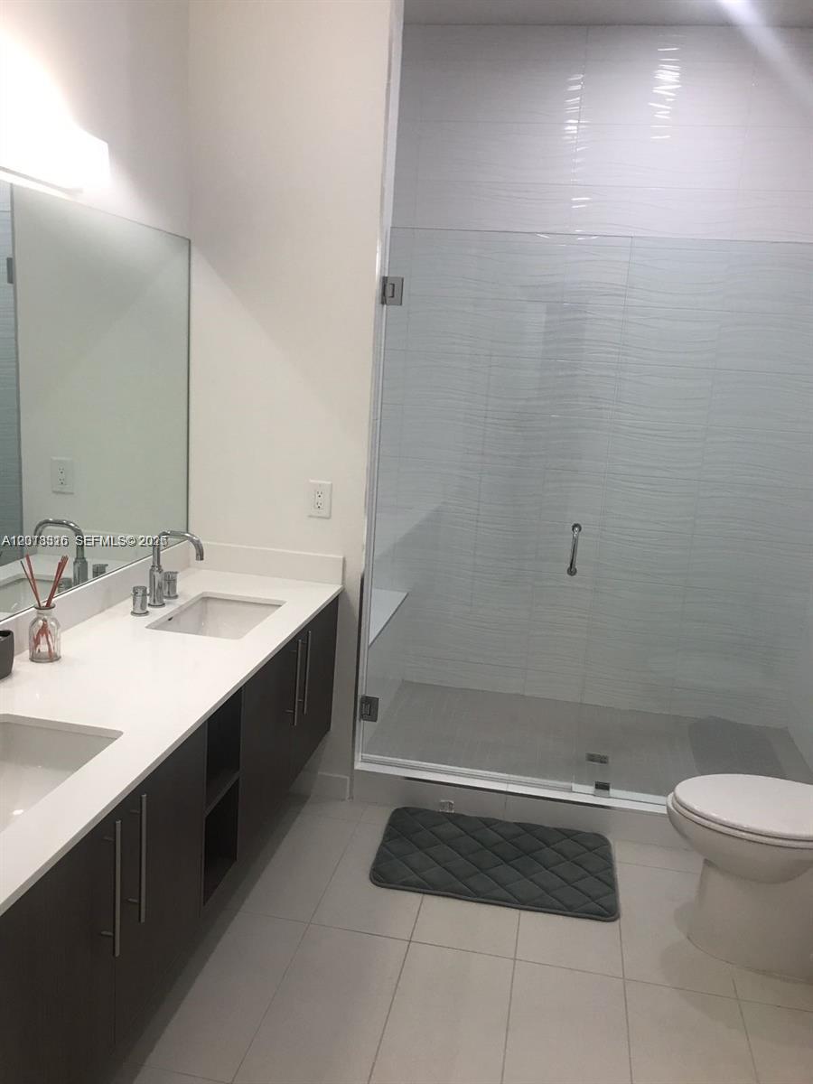 A modern bathroom features a double vanity with dark cabinets, white countertops, and a glass-enclosed shower — 7751 NW 107th Ave # 803, Doral FL 33178, DORAL, FL