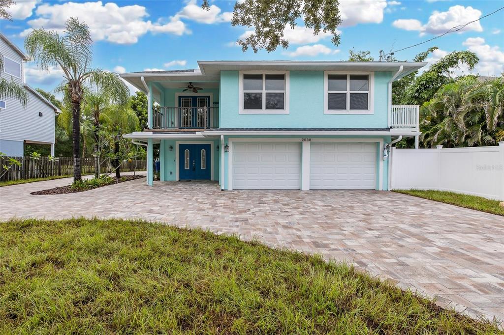 A two-story light blue house features a paved driveway, a two-car garage, and a balcony — 2030 GULFVIEW DRIVE, HOLIDAY, FL