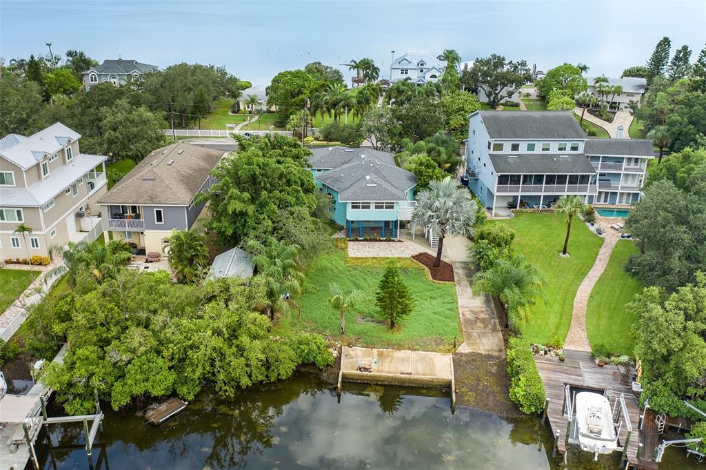 An aerial view shows three waterfront houses with lawns, trees, and private boat docks — 2030 GULFVIEW DRIVE, HOLIDAY, FL