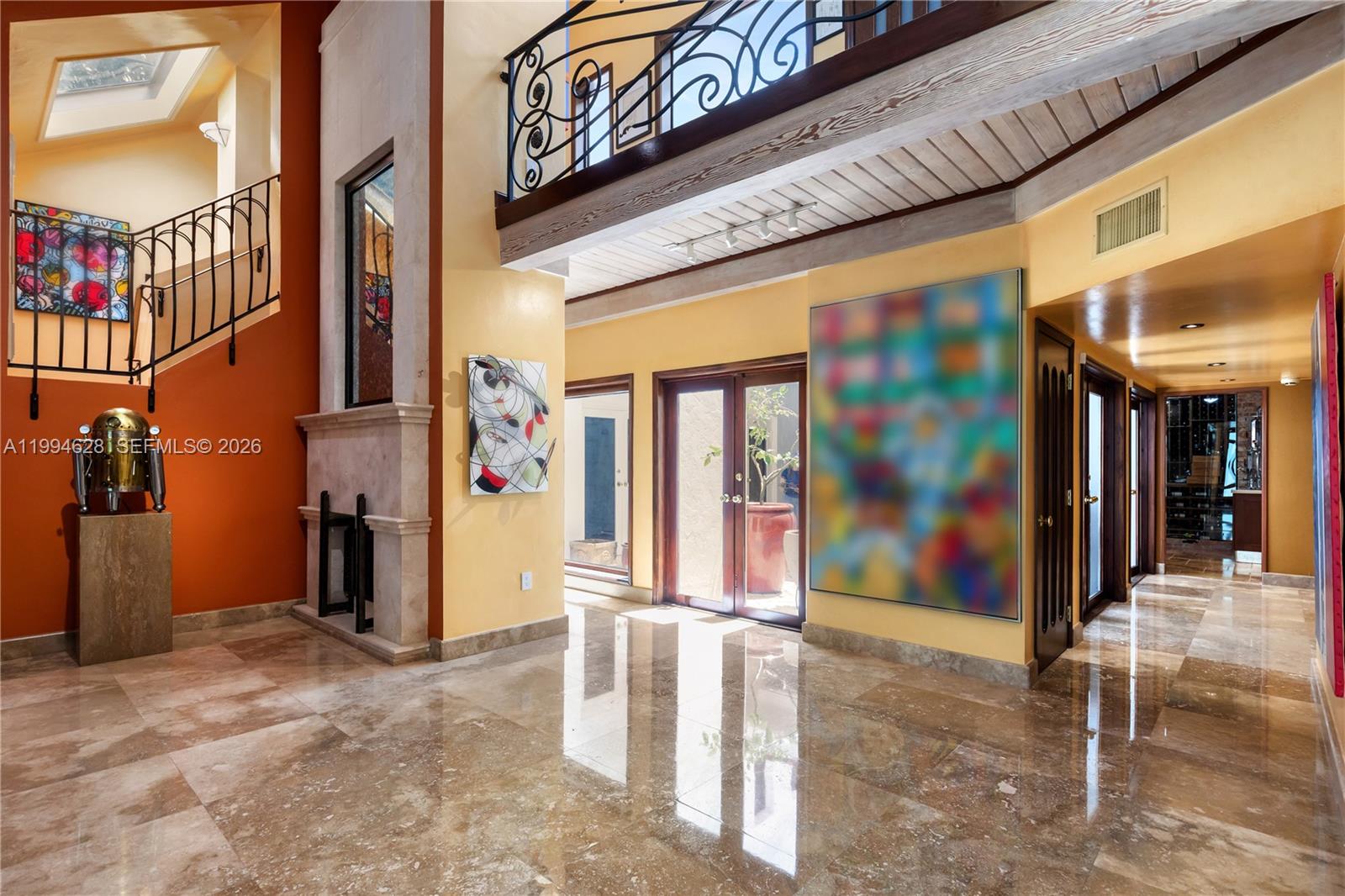 A spacious foyer features marble floors, a stone fireplace, and a wrought iron staircase — 20251 W Oak Haven Cir, Miami FL 33179, MIAMI, FL