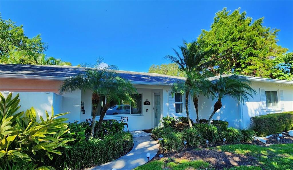 A single-story house with a white exterior, palm trees, and a walkway leading to the entrance — 329 BERNARD AVENUE, SARASOTA, FL