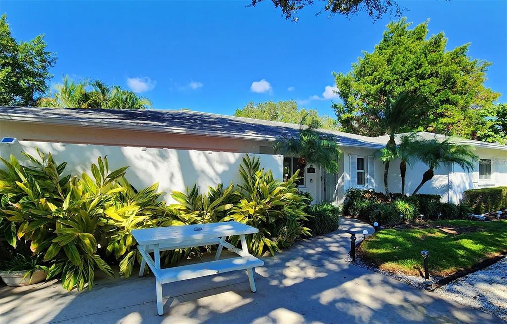 A white picnic table sits on a concrete patio in front of a single-story house — 329 BERNARD AVENUE, SARASOTA, FL