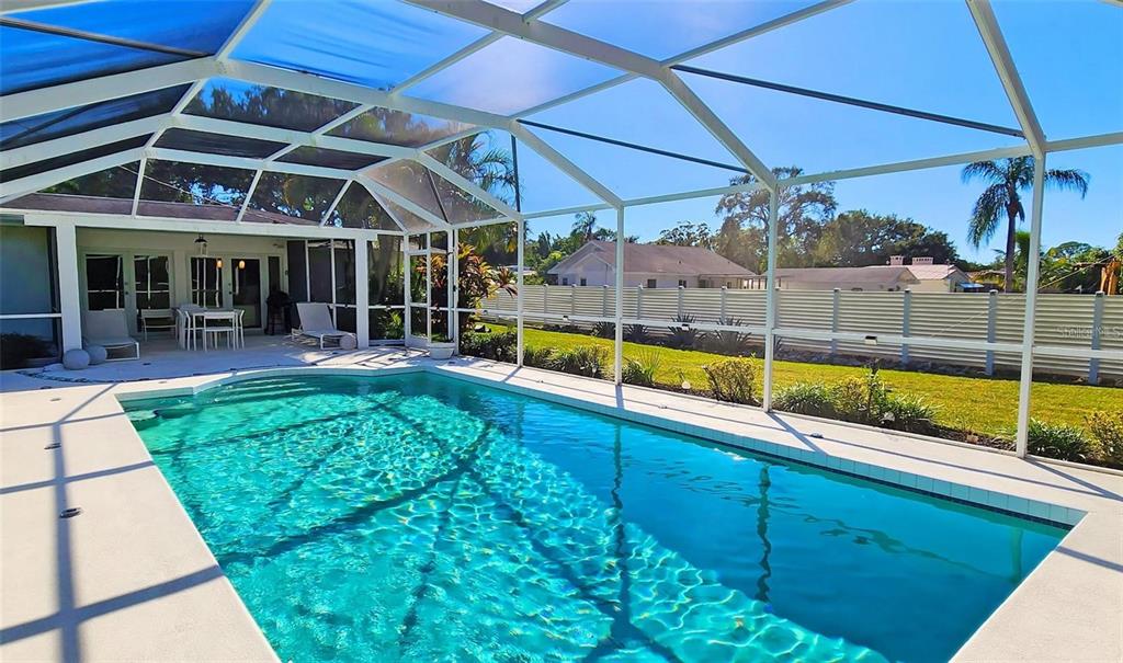 A swimming pool with a screened-in lanai and a white fence in the backyard — 329 BERNARD AVENUE, SARASOTA, FL