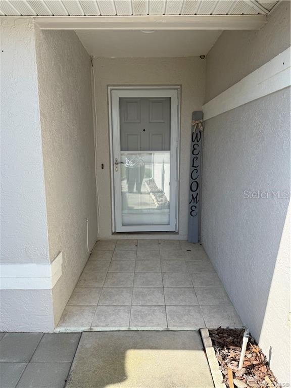 A covered entryway features a tiled floor, a white storm door, and a welcome sign — 838 W BOGART COURT, BEVERLY HILLS, FL