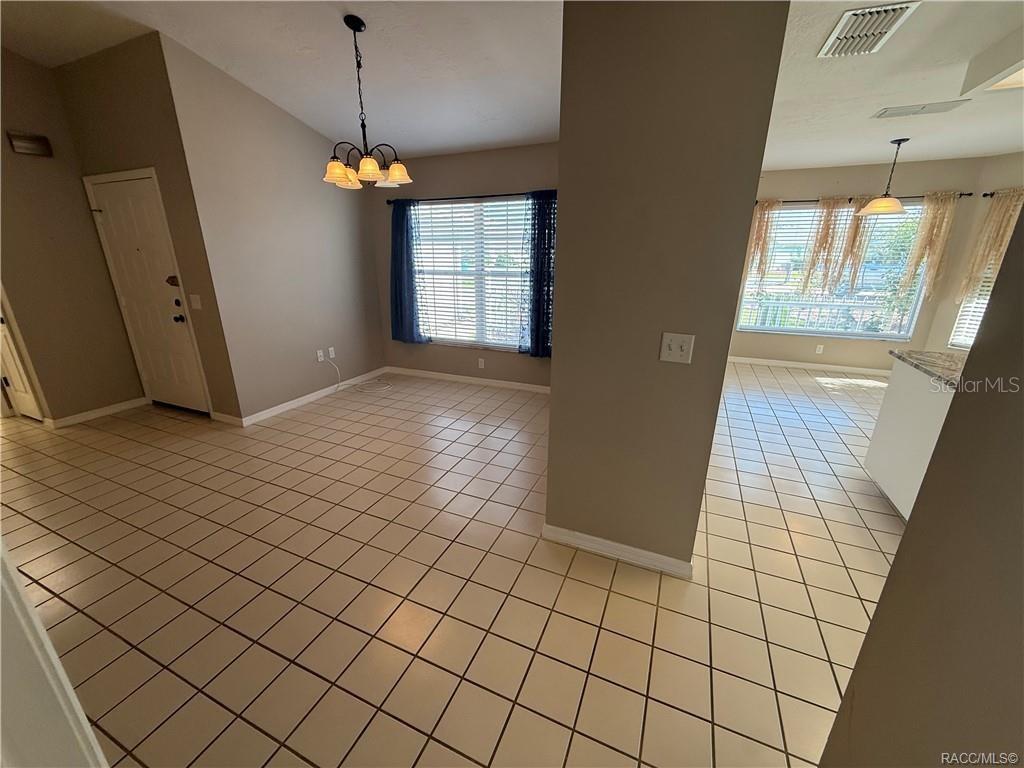 An open dining area with tile flooring, a chandelier, and a view into the kitchen — 838 W BOGART COURT, BEVERLY HILLS, FL