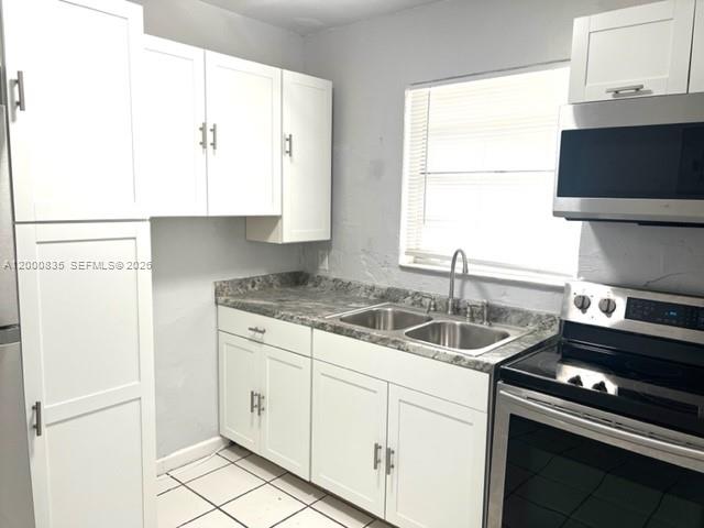 A kitchen features white cabinets, a double sink, and stainless steel appliances — 504 N 57th Ave, Hollywood FL 33021, HOLLYWOOD, FL