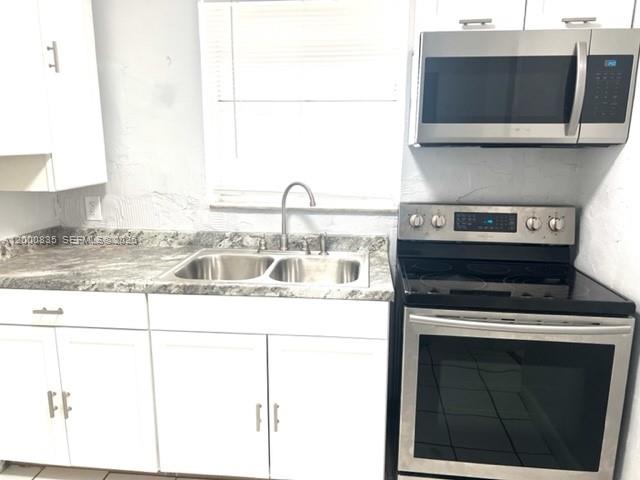 A kitchen features white cabinets, a stainless steel microwave, and a stainless steel electric range — 504 N 57th Ave, Hollywood FL 33021, HOLLYWOOD, FL