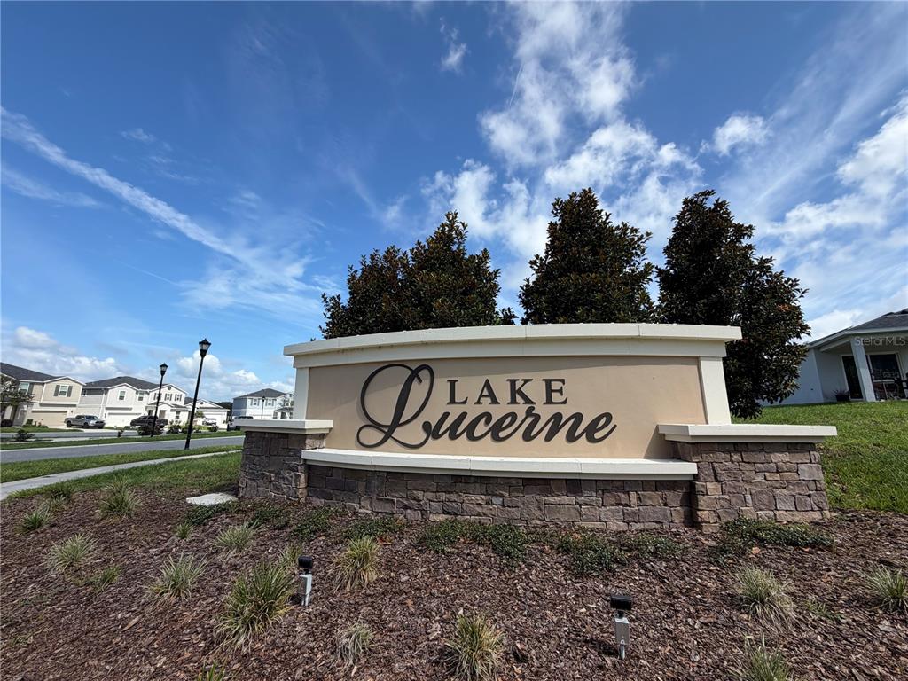 A stone and stucco monument sign for Lake Lucerne stands in a landscaped residential area — 1127 SEEDORF DRIVE, WINTER HAVEN, FL