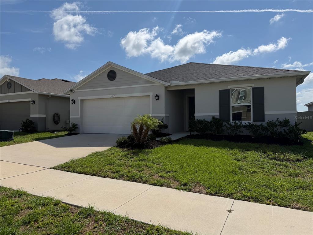 A single-story house with a two-car garage, gray siding, and a front lawn — 1127 SEEDORF DRIVE, WINTER HAVEN, FL