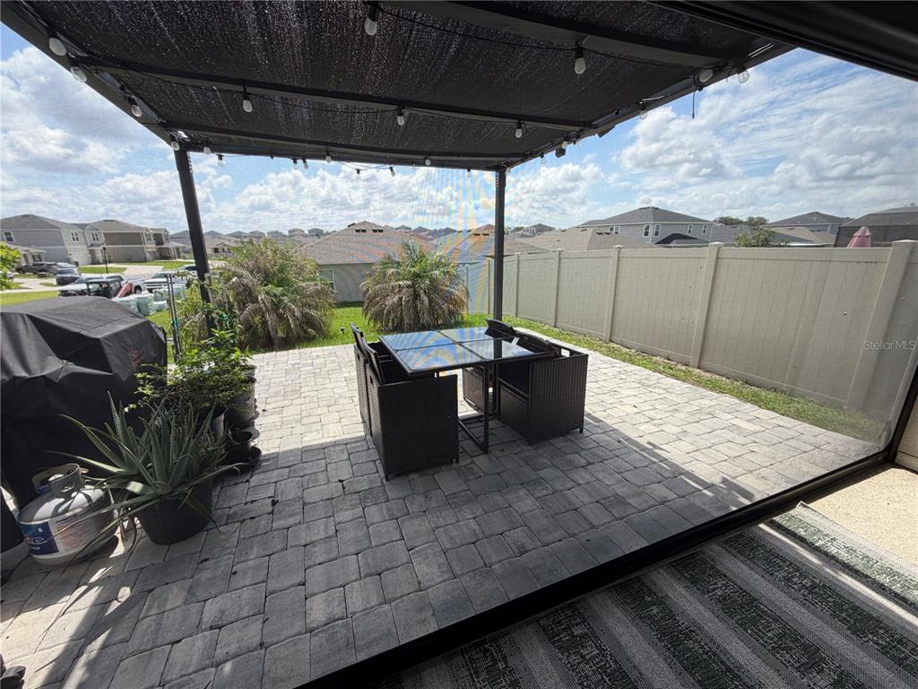 A paved patio features a dining set under a pergola with string lights — 1127 SEEDORF DRIVE, WINTER HAVEN, FL