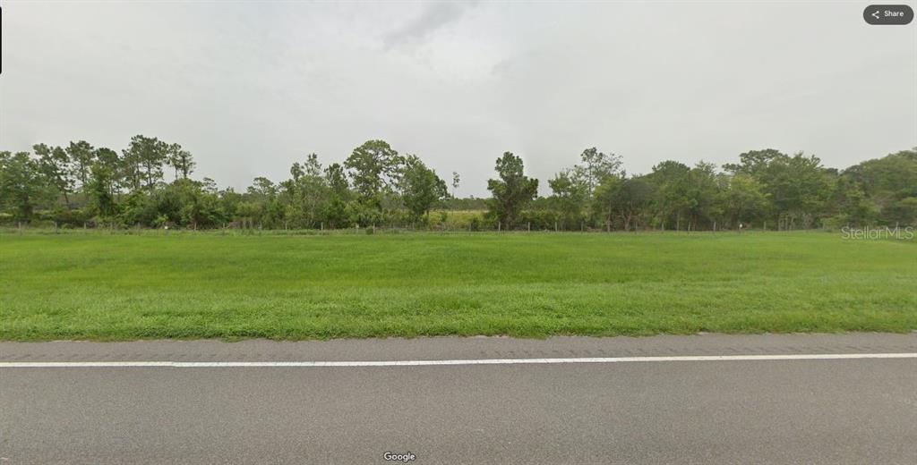 A flat, grassy vacant lot sits alongside a paved road with trees in the background — S KENANSVILLE ROAD, OKEECHOBEE, FL