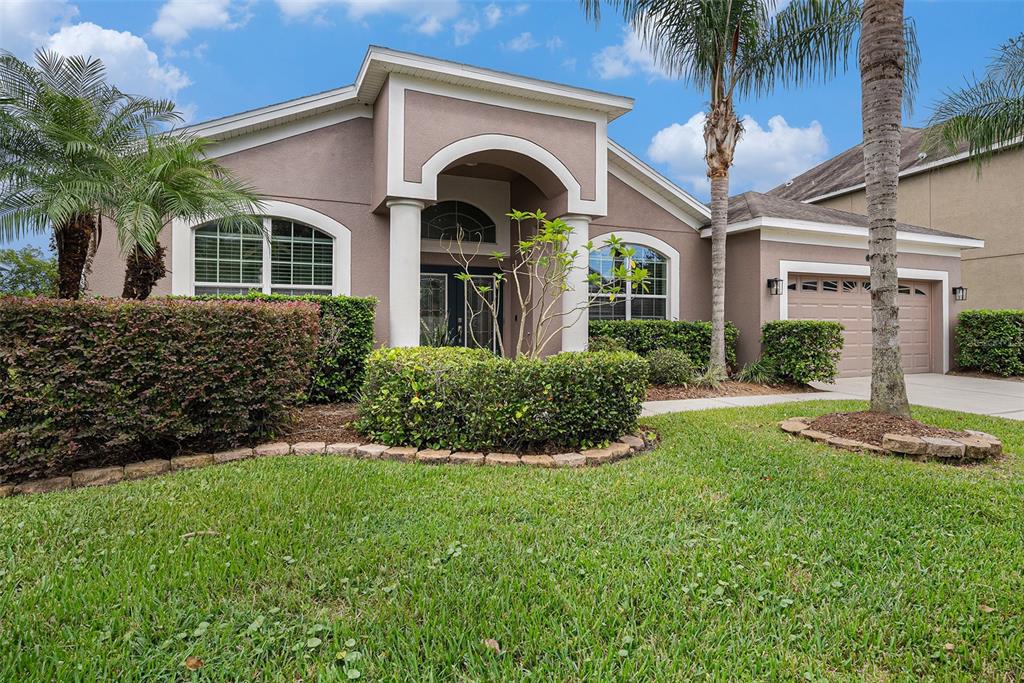 A single-story house with a tan stucco exterior, arched windows, and a two-car garage — 20017 PAINTING NATURE LANE, TAMPA, FL