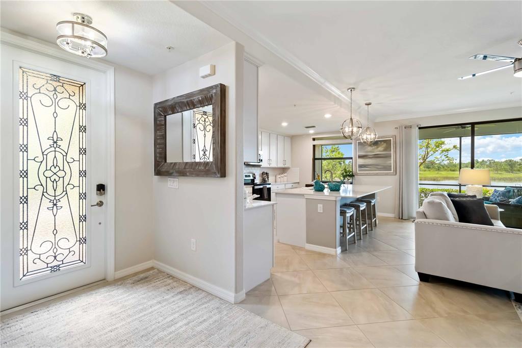 An entryway leads into an open-concept kitchen and living area with tile flooring — 10805 TARFLOWER DRIVE UNIT 101, VENICE, FL