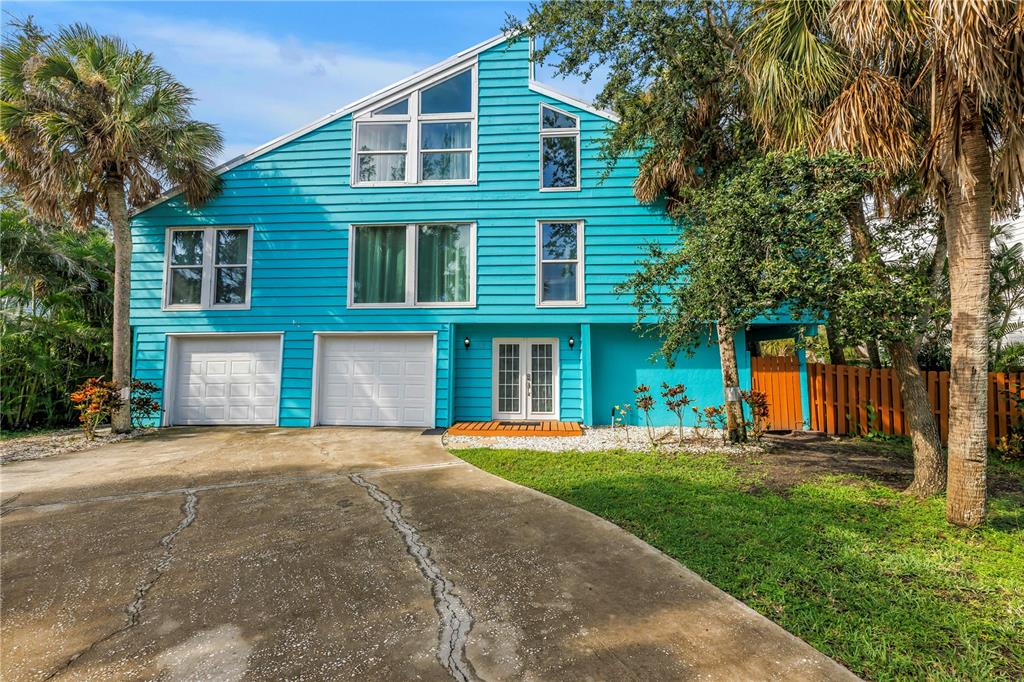 A bright blue three-story house with two garage doors and a front entrance — 156 SIESTA DRIVE, SARASOTA, FL