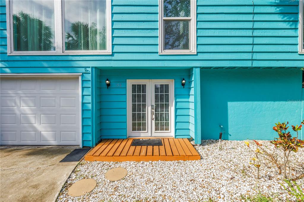 The exterior of a blue house features a white garage door and double glass doors — 156 SIESTA DRIVE, SARASOTA, FL