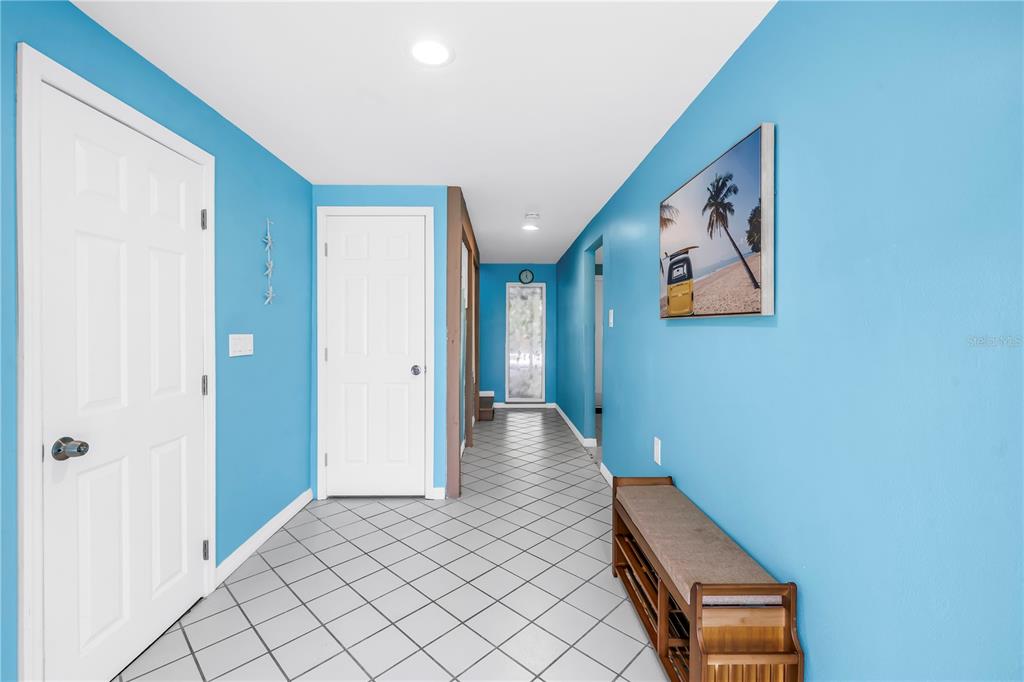 A hallway with bright blue walls, white doors, and gray diamond-patterned tile flooring — 156 SIESTA DRIVE, SARASOTA, FL