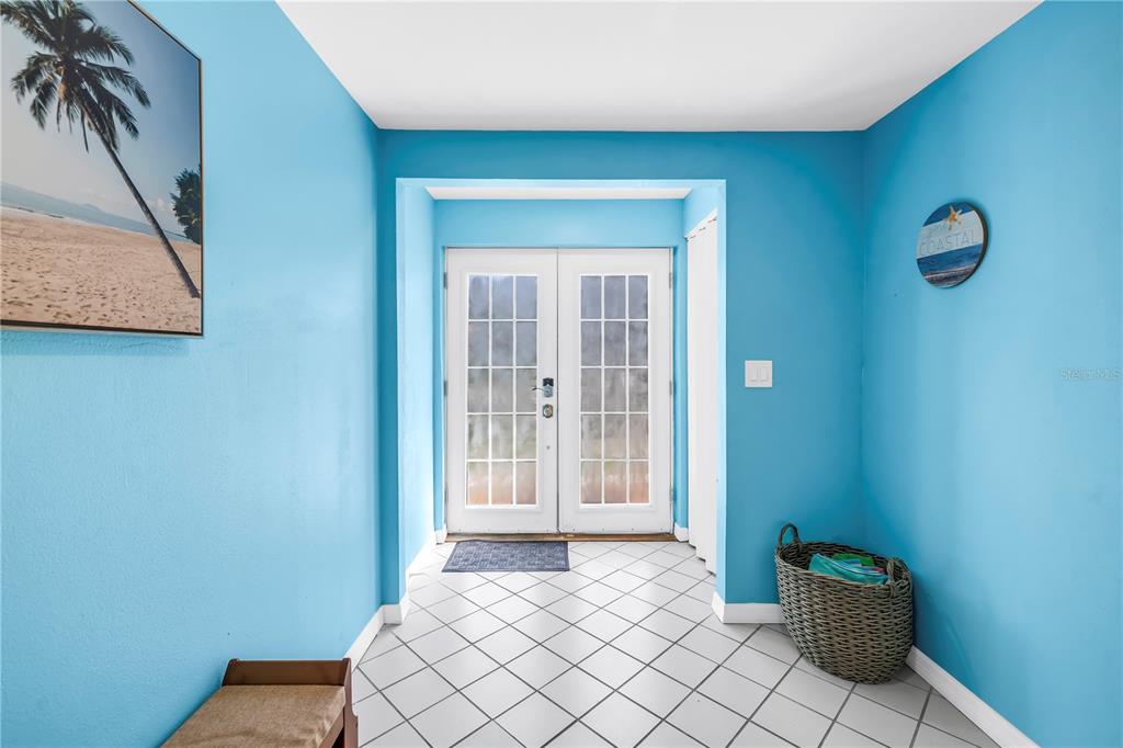 An entryway with bright blue walls, white tiled floors, and double glass doors — 156 SIESTA DRIVE, SARASOTA, FL