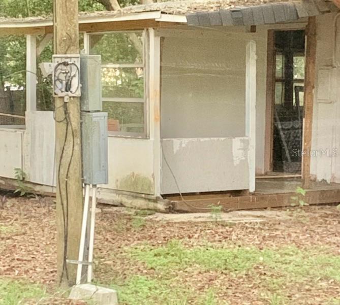 A weathered exterior view of a house featuring a porch with unfinished wall panels — 17273 NE 37TH STREET, SILVER SPRINGS, FL