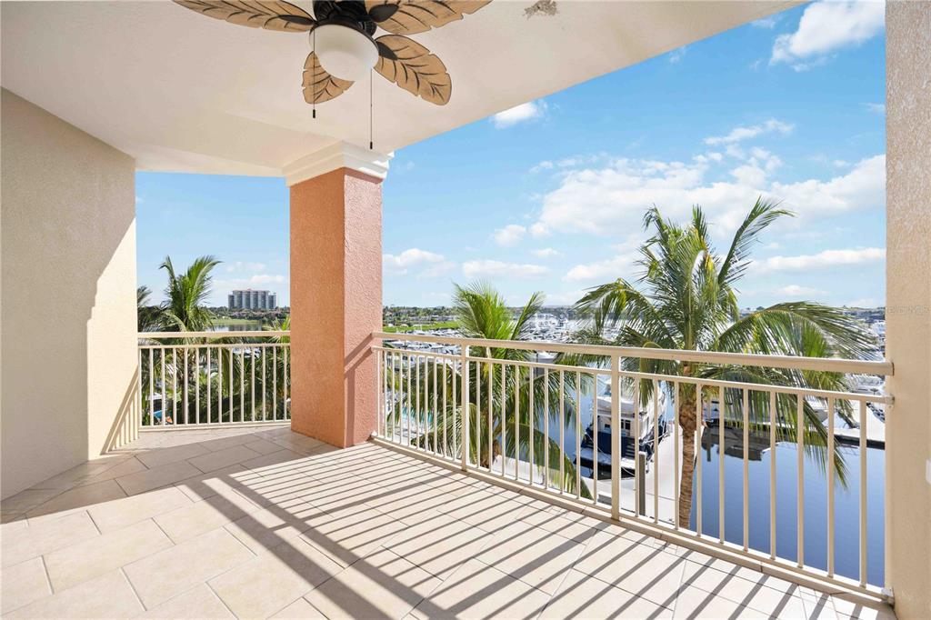 A covered balcony features tile flooring, a ceiling fan, and a view of a marina — 606 RIVIERA DUNES WAY UNIT 302, PALMETTO, FL