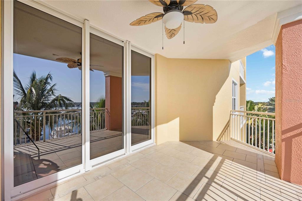 A covered balcony with tiled flooring, a ceiling fan, and sliding glass doors overlooking water — 606 RIVIERA DUNES WAY UNIT 302, PALMETTO, FL