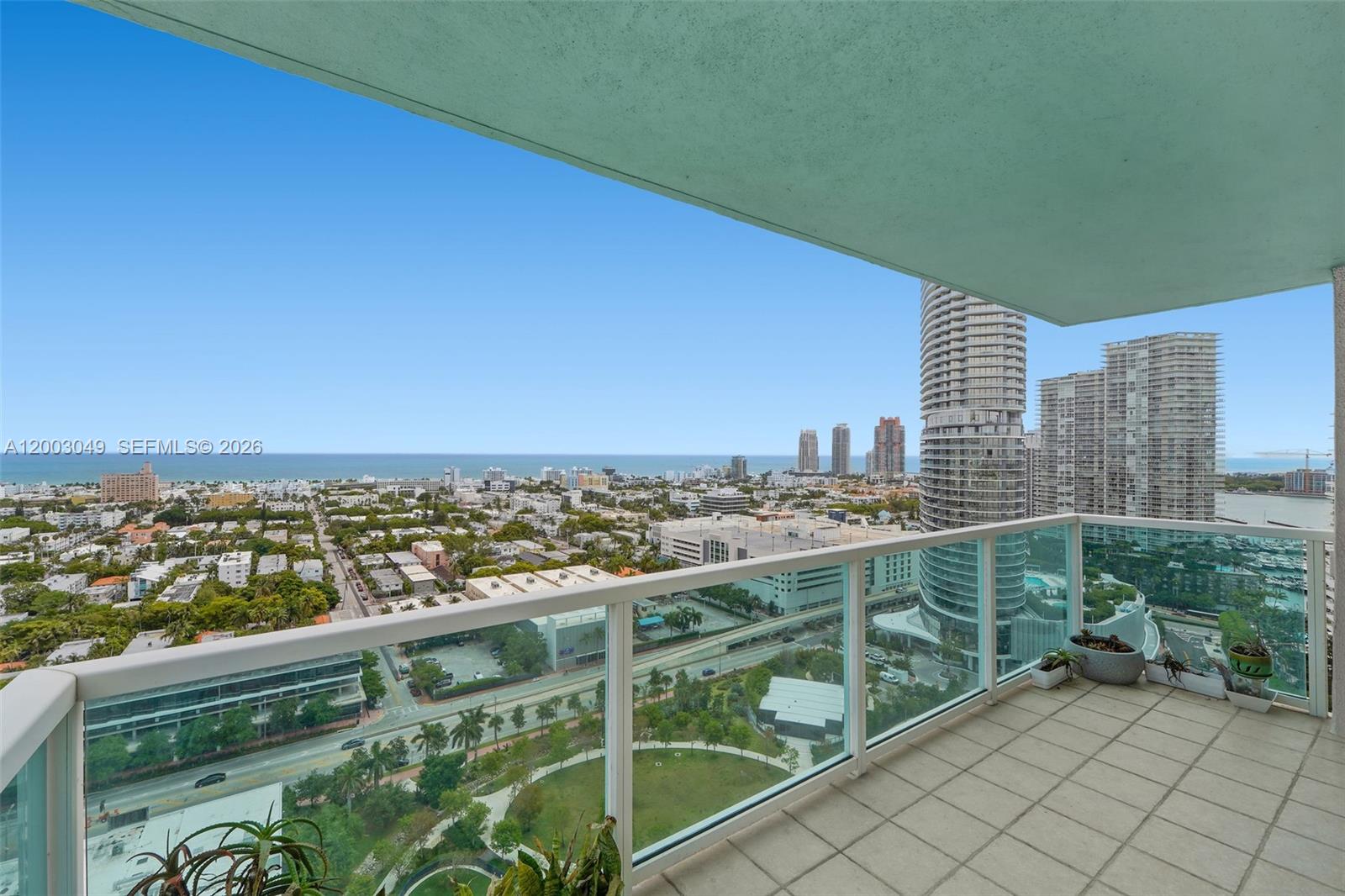 A high-rise balcony overlooks a city, a park, and the ocean in the distance — 650 West Ave # 2612, Miami Beach FL 33139, MIAMI BEACH, FL