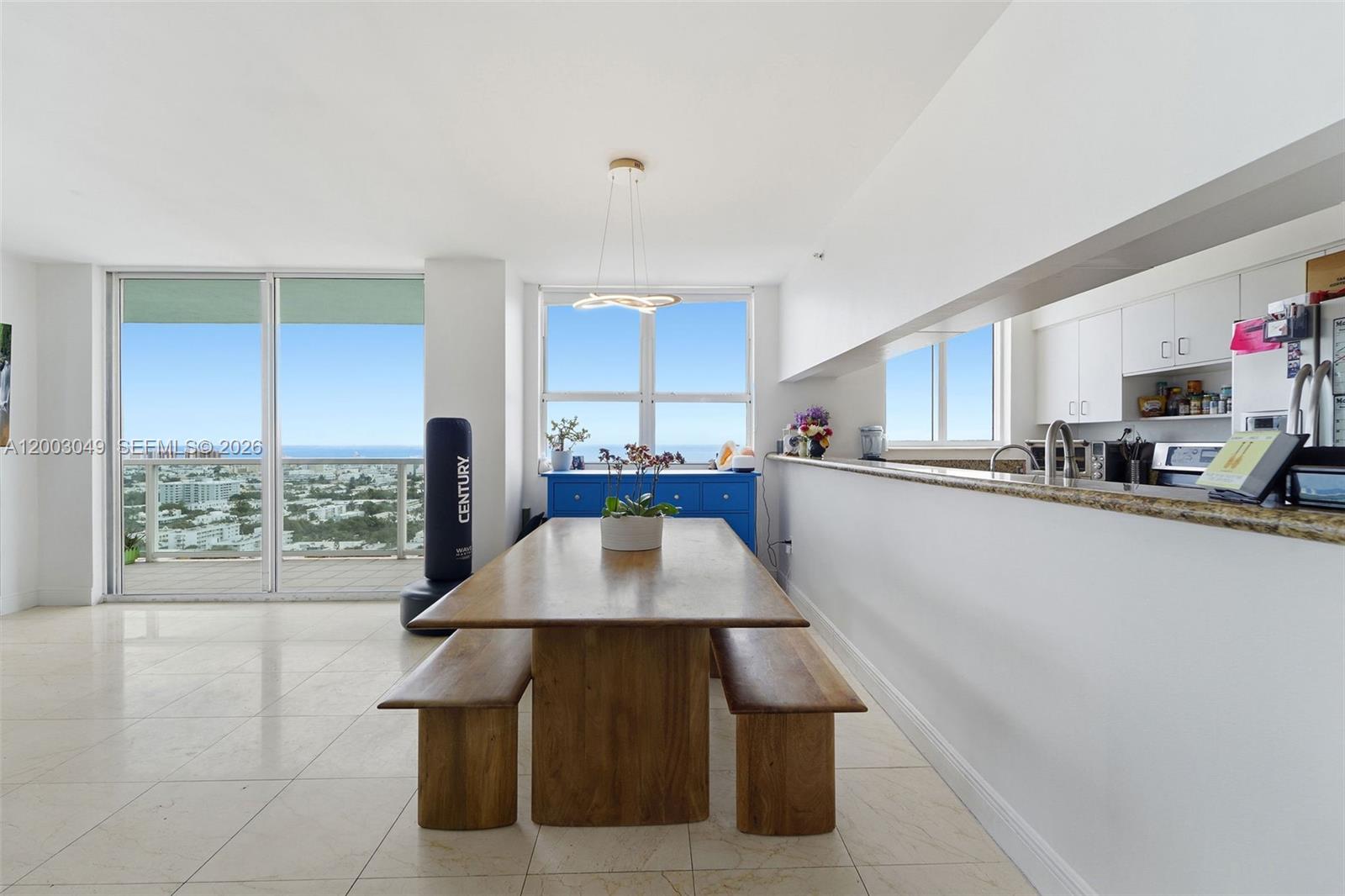 A dining area features a wooden table with benches, tile floors, and a kitchen pass-through — 650 West Ave # 2612, Miami Beach FL 33139, MIAMI BEACH, FL