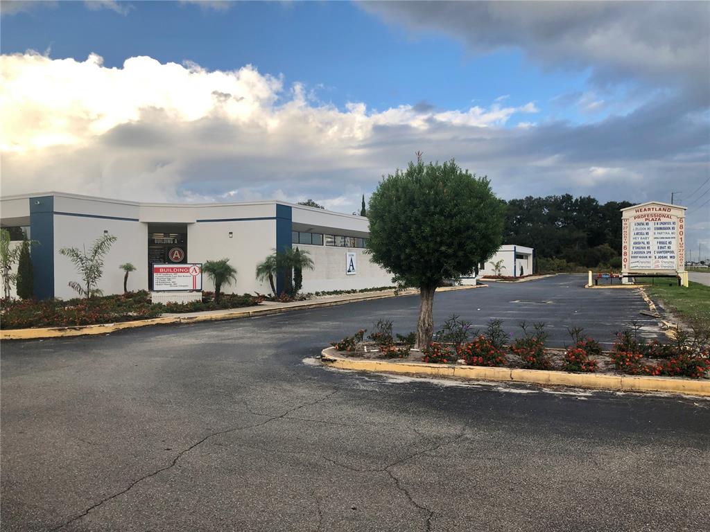 A low-rise commercial building with a parking lot and a directory sign in the foreground — 6801 US 27 HIGHWAY N UNIT C1+2, SEBRING, FL
