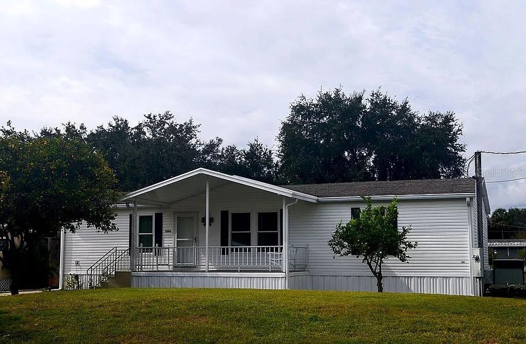 A white single-story manufactured home features a front porch with metal railings and stairs — 2086 STARBOARD DRIVE, GENEVA, FL