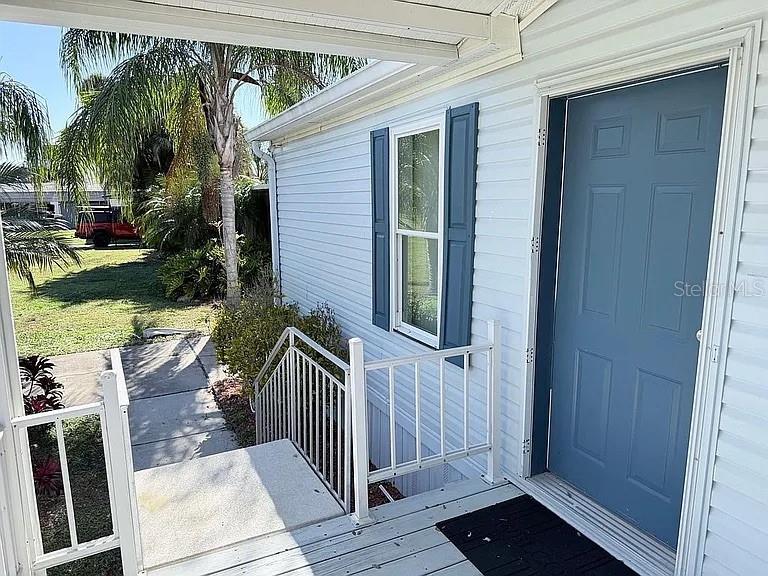 A blue front door with white siding and a metal railing leads to a porch — 2086 STARBOARD DRIVE, GENEVA, FL