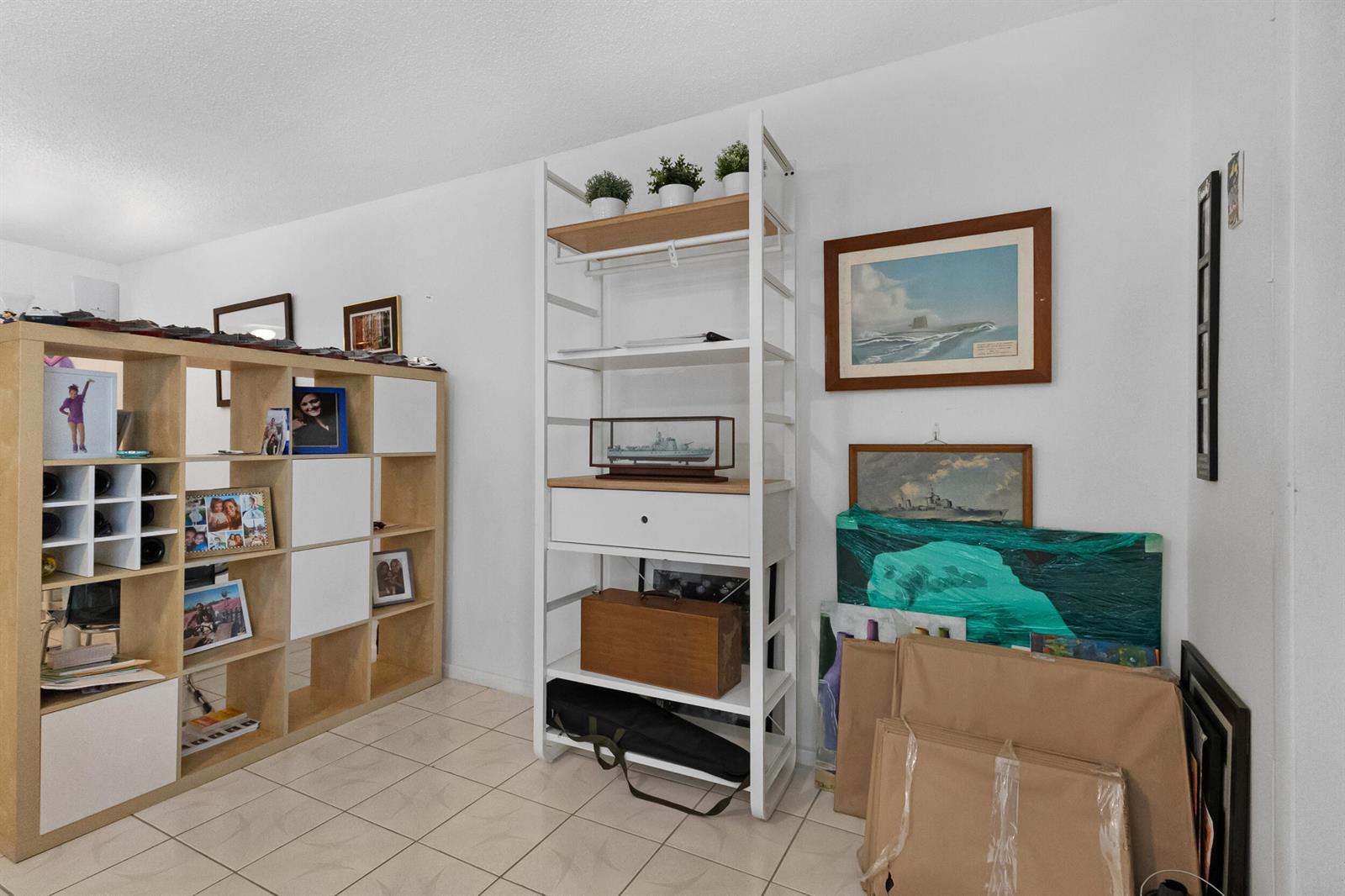 A room features a light wood cube storage unit, a white metal shelving unit, and artwork — 18 Prescott A, Deerfield Beach FL 33442, DEERFIELD BEACH, FL