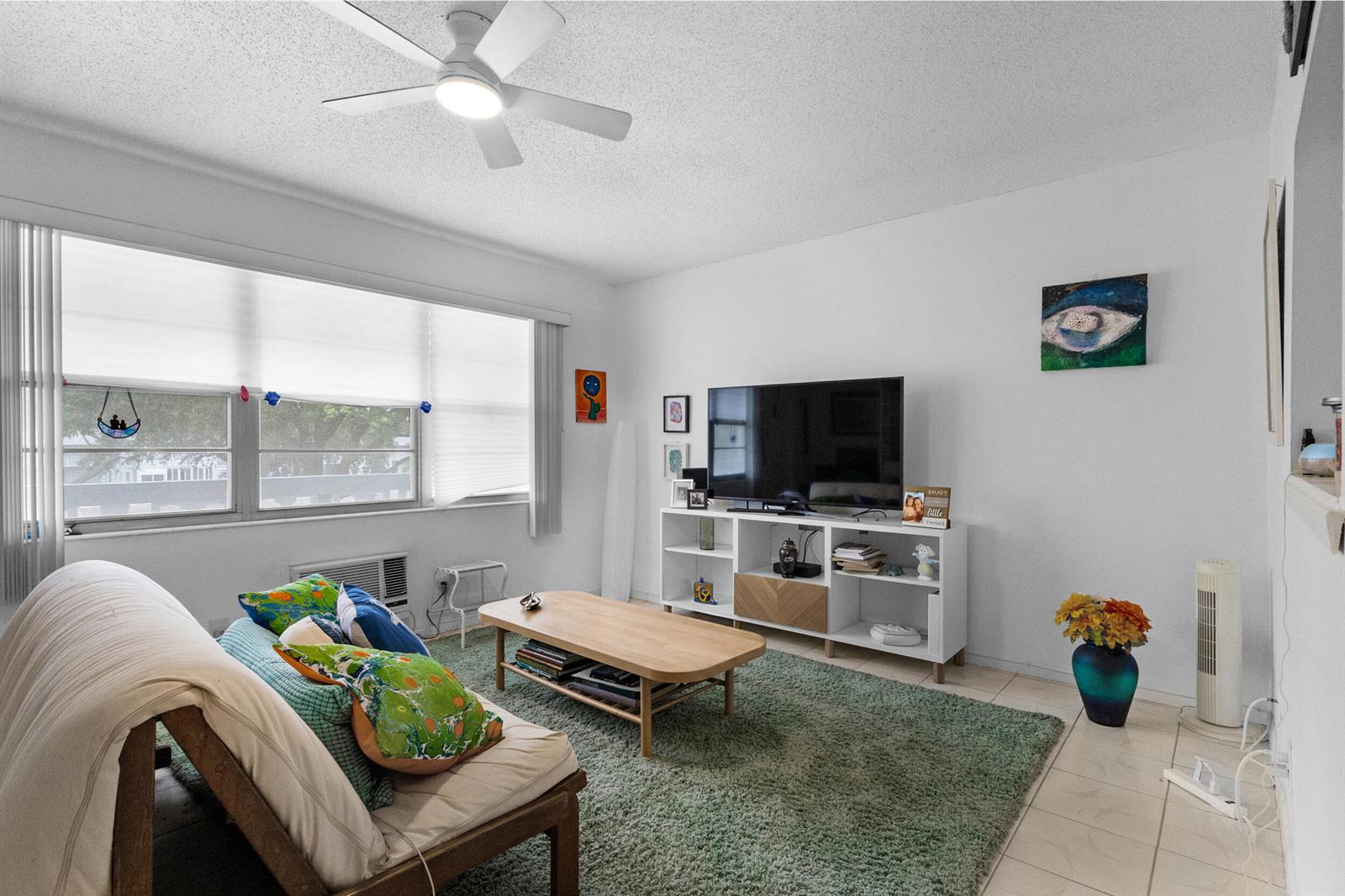 A living room features a futon, coffee table, television on a media console, and rug — 18 Prescott A, Deerfield Beach FL 33442, DEERFIELD BEACH, FL