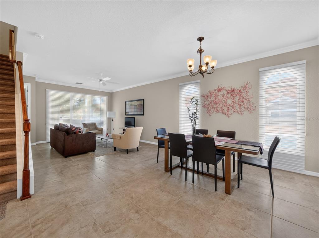 A dining room features a glass-topped table, dark chairs, and a red coral wall sculpture — 8915 DELLA SCALA CIRCLE, ORLANDO, FL