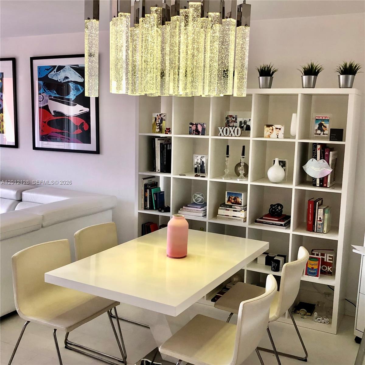 A dining area features a white table, four chairs, a large shelving unit, and a chandelier — 90 Alton Rd # 307, Miami Beach FL 33139, MIAMI BEACH, FL