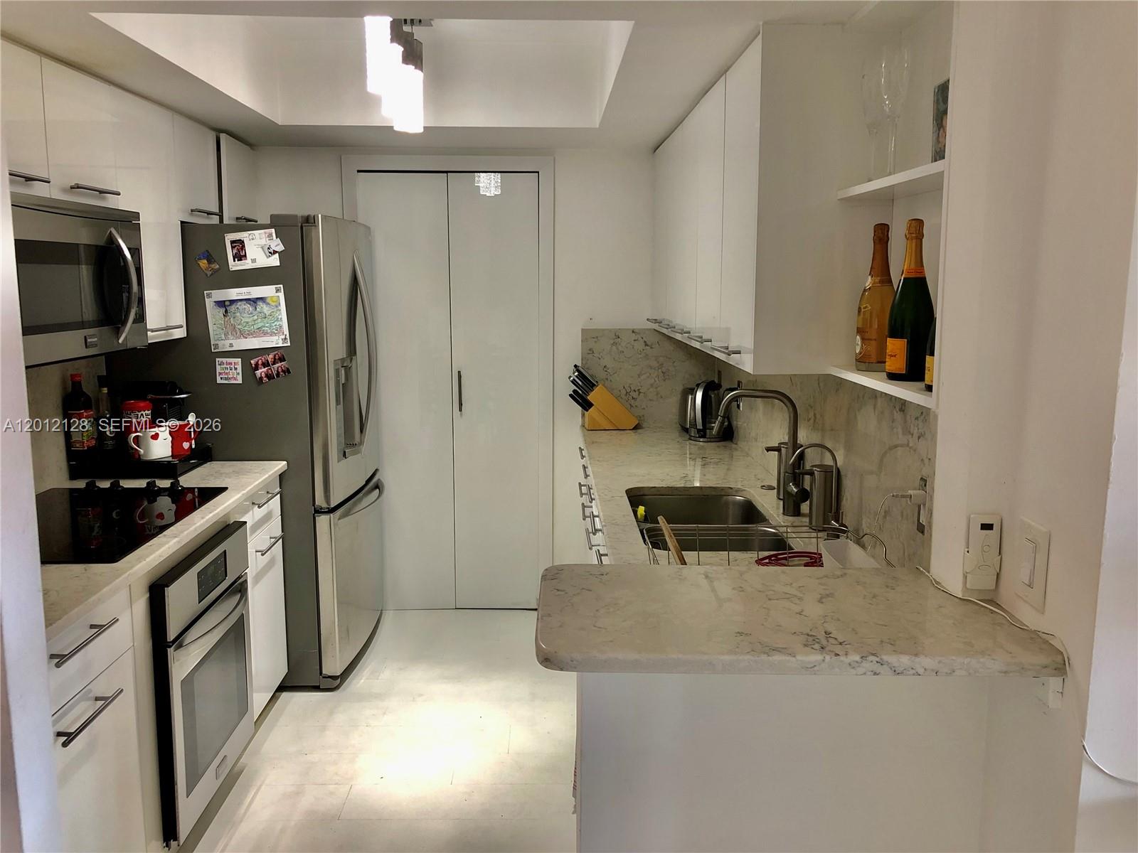 A modern kitchen features white cabinetry, stainless steel appliances, and marble-patterned countertops — 90 Alton Rd # 307, Miami Beach FL 33139, MIAMI BEACH, FL