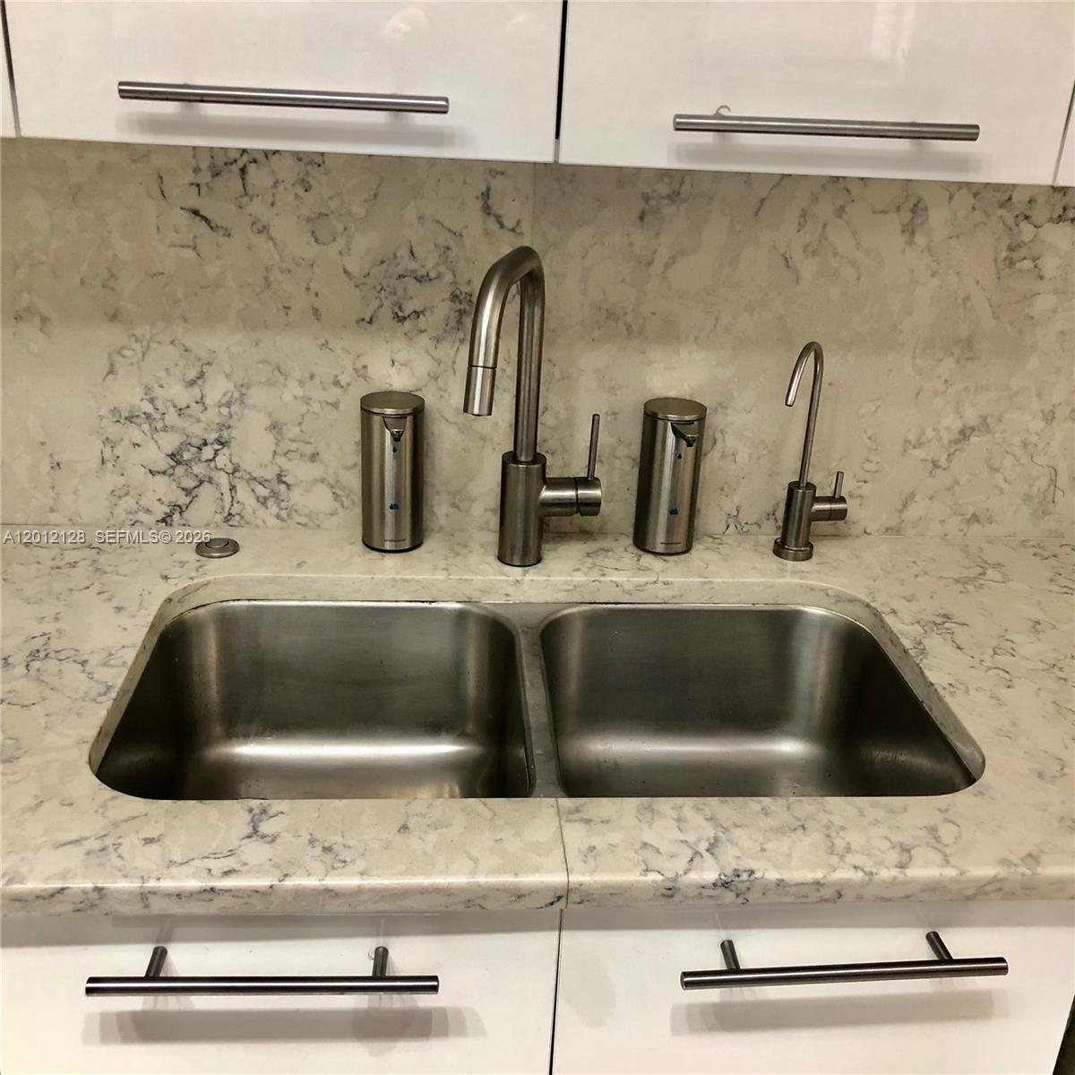 A stainless steel double-basin kitchen sink with a faucet and soap dispensers in a countertop — 90 Alton Rd # 307, Miami Beach FL 33139, MIAMI BEACH, FL