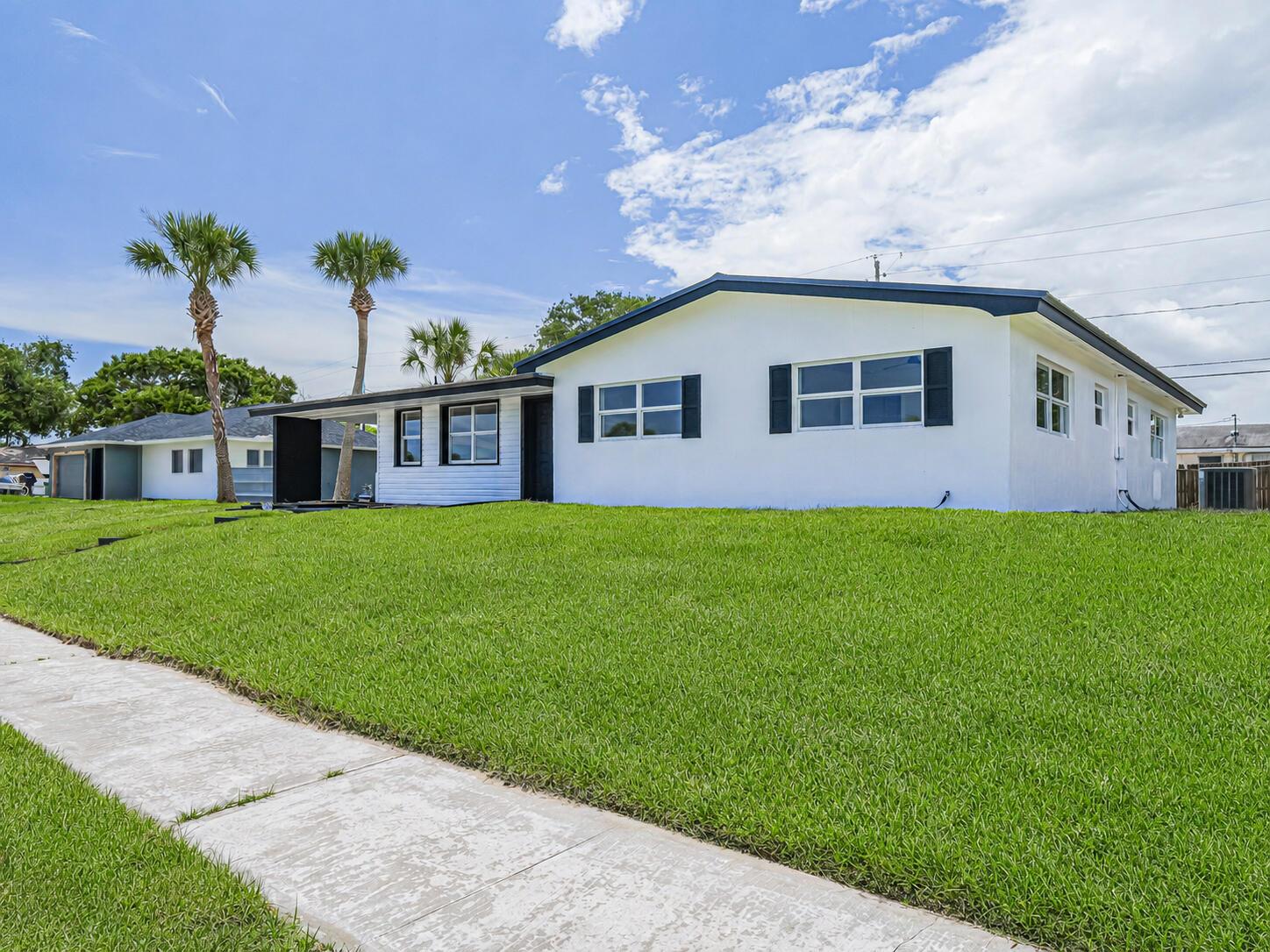 A white single-story house with black trim and shutters sits behind a large green lawn — 375 Manly Avenue, Sebastian FL 32958, SEBASTIAN, FL
