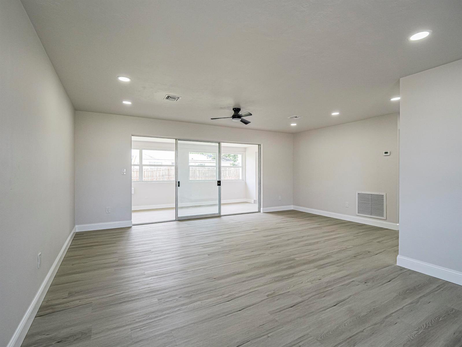 An empty living room features light wood-look flooring, recessed lighting, a ceiling fan, and sliding doors — 375 Manly Avenue, Sebastian FL 32958, SEBASTIAN, FL
