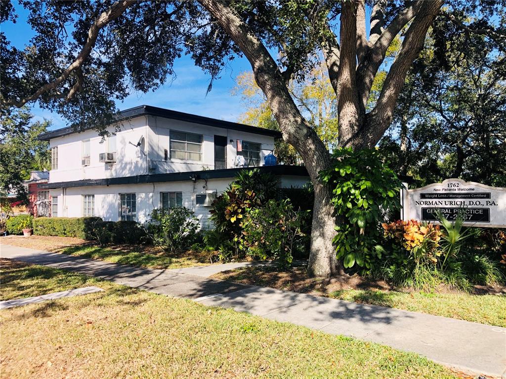 A two-story white building with a sign for a medical practice stands behind a tree — 1762 N FORT HARRISON AVENUE, CLEARWATER, FL