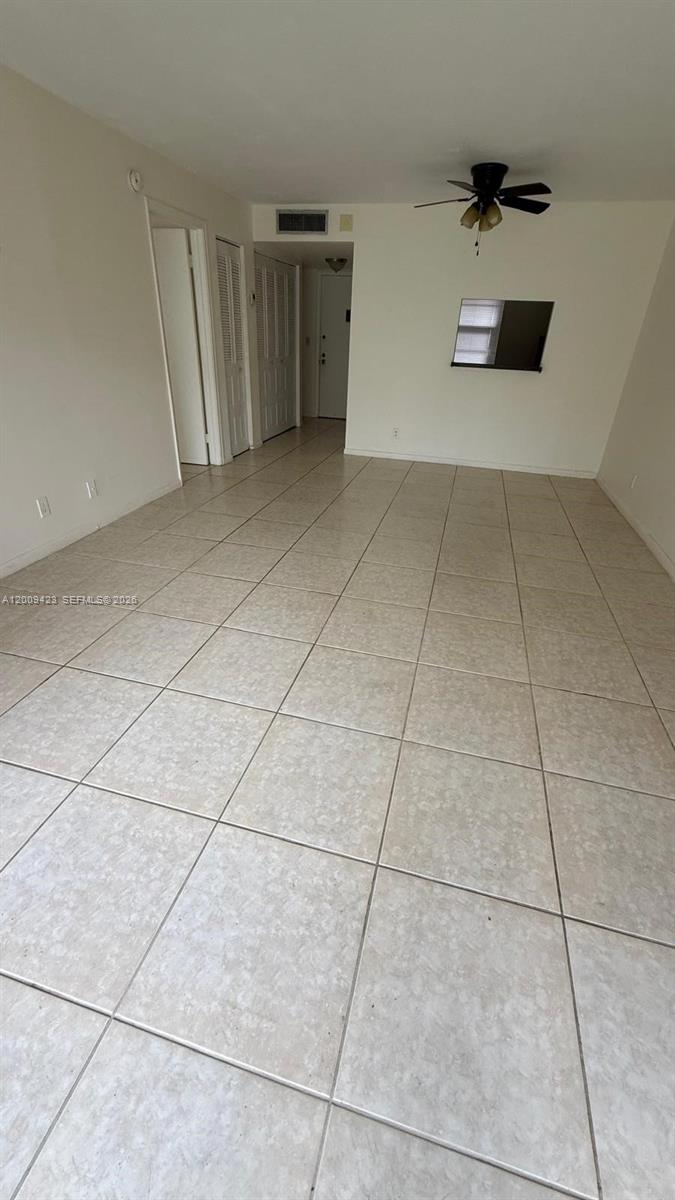 An empty room features light-colored tile flooring, white walls, and a ceiling fan — 3774 Inverrary Blvd # 105P, Lauderhill FL 33319, LAUDERHILL, FL