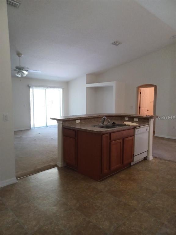 A kitchen island with a sink and dishwasher overlooks an open living area — 63 BANNBURY LANE, PALM COAST, FL