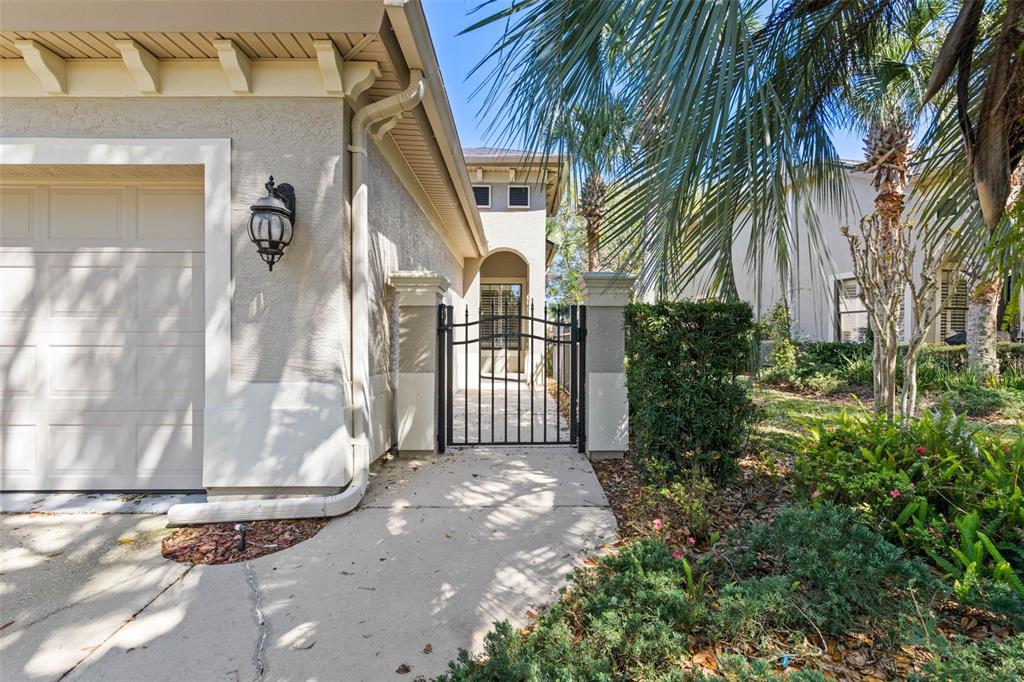 A concrete walkway leads to a gated courtyard entrance next to a residential garage — 10 RIVER POINT DRIVE, PALM COAST, FL