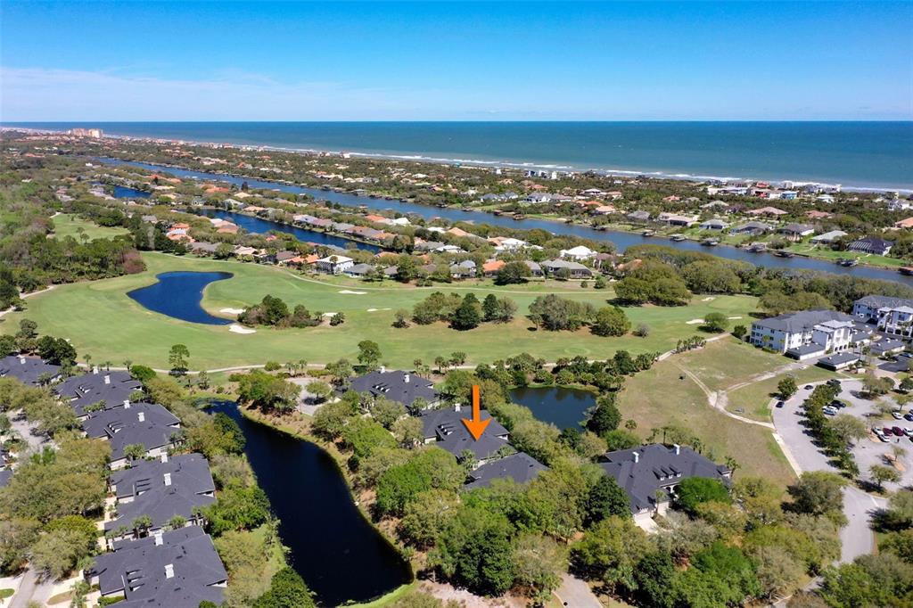 An aerial view shows a residential complex with dark roofs, surrounding ponds, and a golf course — 10 RIVER POINT DRIVE, PALM COAST, FL