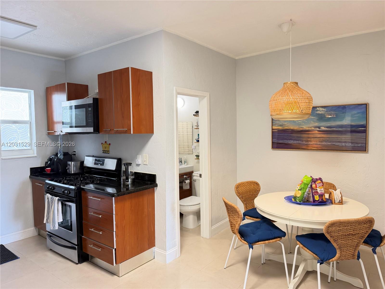 A kitchen with wood cabinets and black countertops sits adjacent to a dining area — 500 14th St # 104, Miami Beach FL 33139, MIAMI BEACH, FL