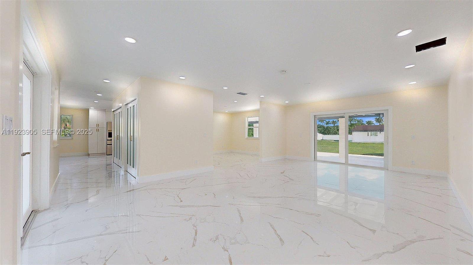 A spacious, empty room features white marble-look tile flooring, recessed lighting, and sliding glass doors — 3801 SW 132nd Ave, Miami FL 33175, MIAMI, FL