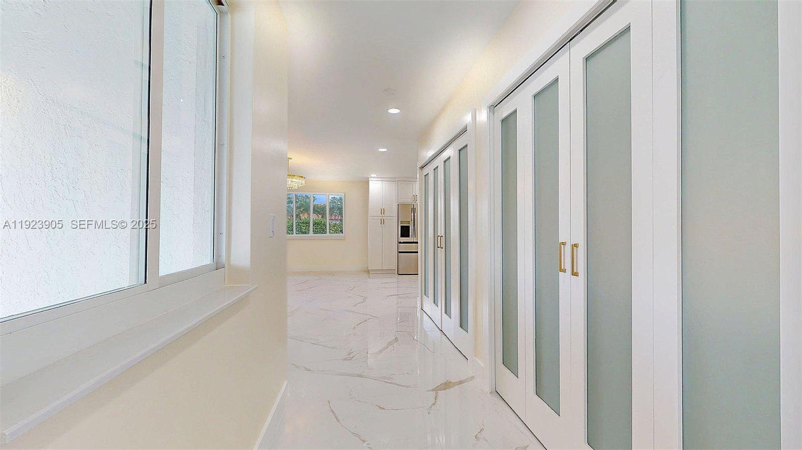 A hallway with white marble floors leads to a kitchen featuring white cabinetry — 3801 SW 132nd Ave, Miami FL 33175, MIAMI, FL