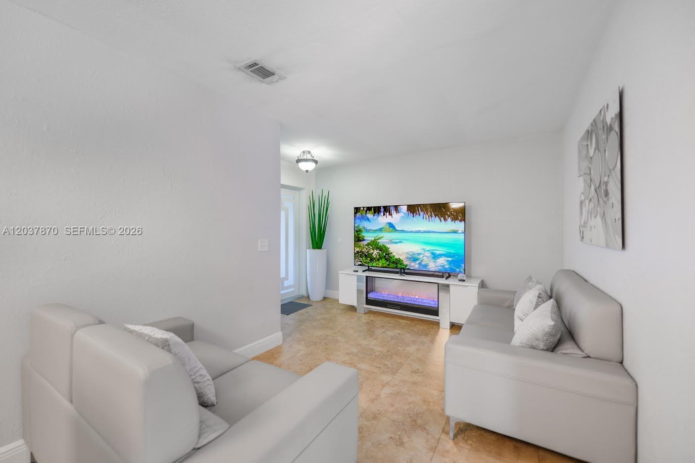 A living room features light tile floors, white walls, a sofa, and a television console — 15216 SW 112th Pl, Miami FL 33157, MIAMI, FL