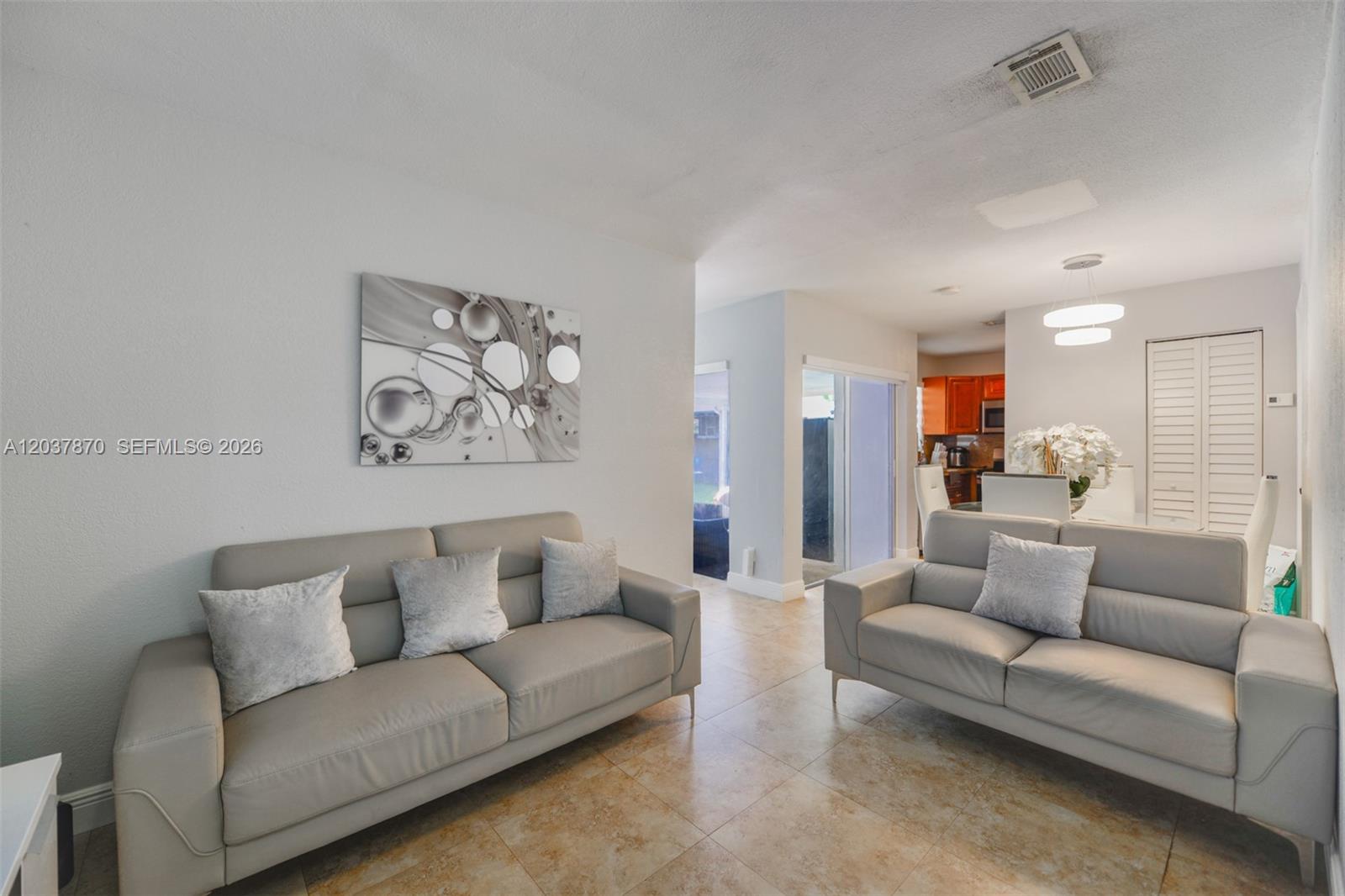 A living room features two light gray leather sofas, tile flooring, and abstract wall art — 15216 SW 112th Pl, Miami FL 33157, MIAMI, FL
