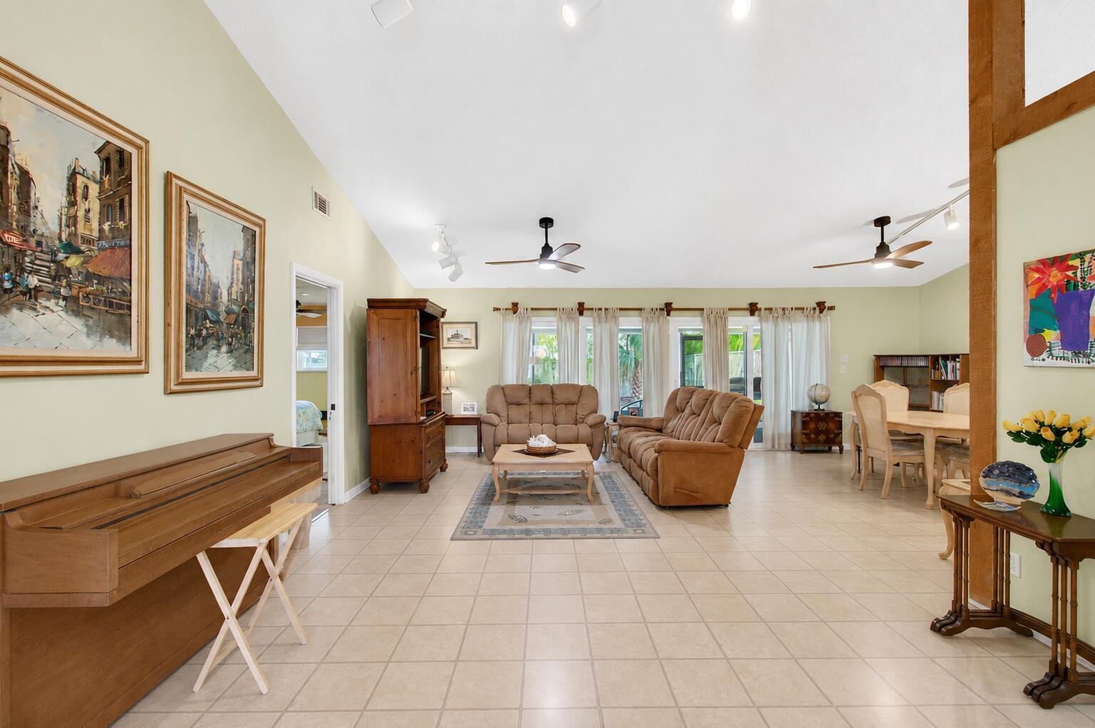 A spacious living and dining room with tile floors, vaulted ceilings, and wooden furniture — 2400 SW 19th Avenue, Boynton Beach FL 33426, BOYNTON BEACH, FL